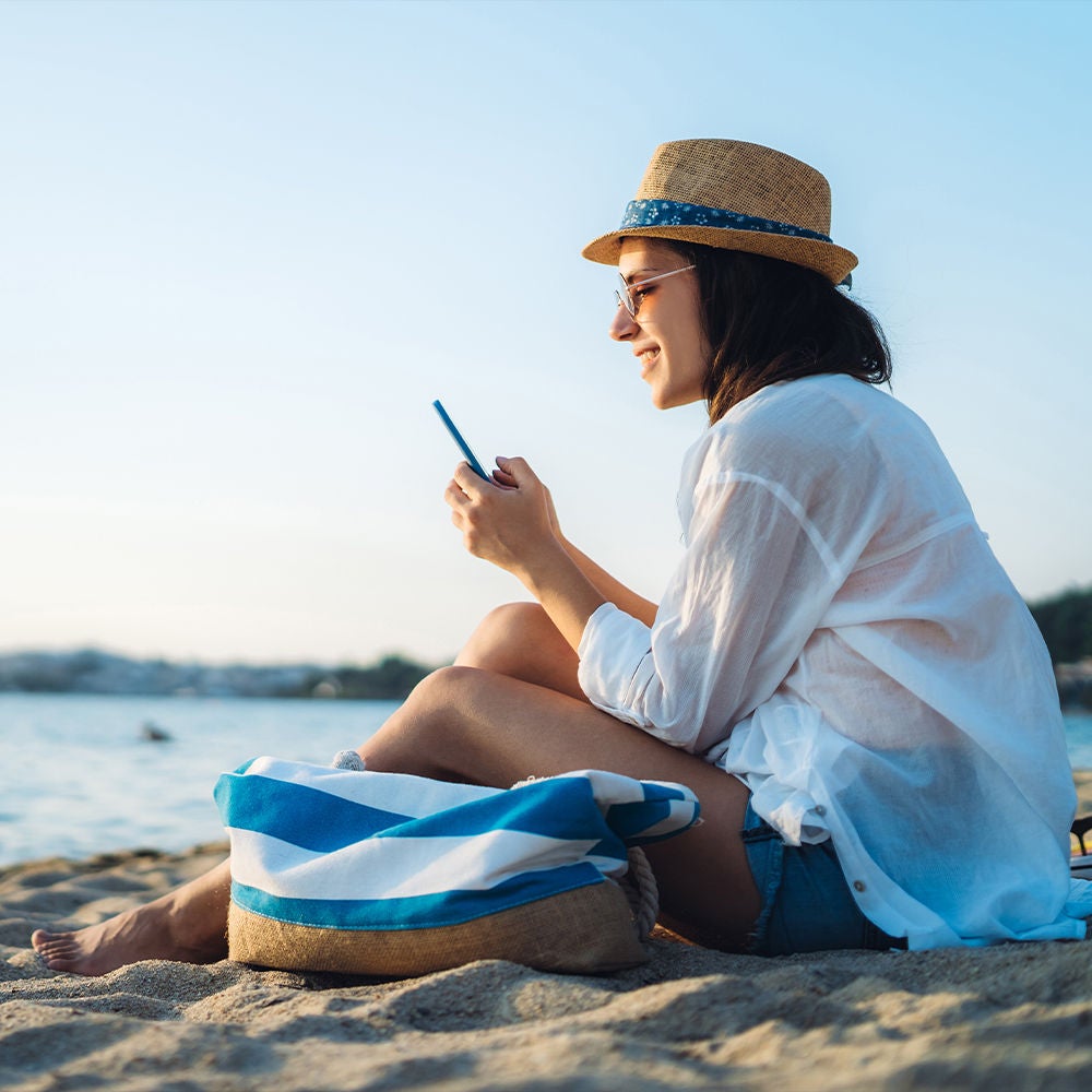 Mujer en la playa, en su teléfono.